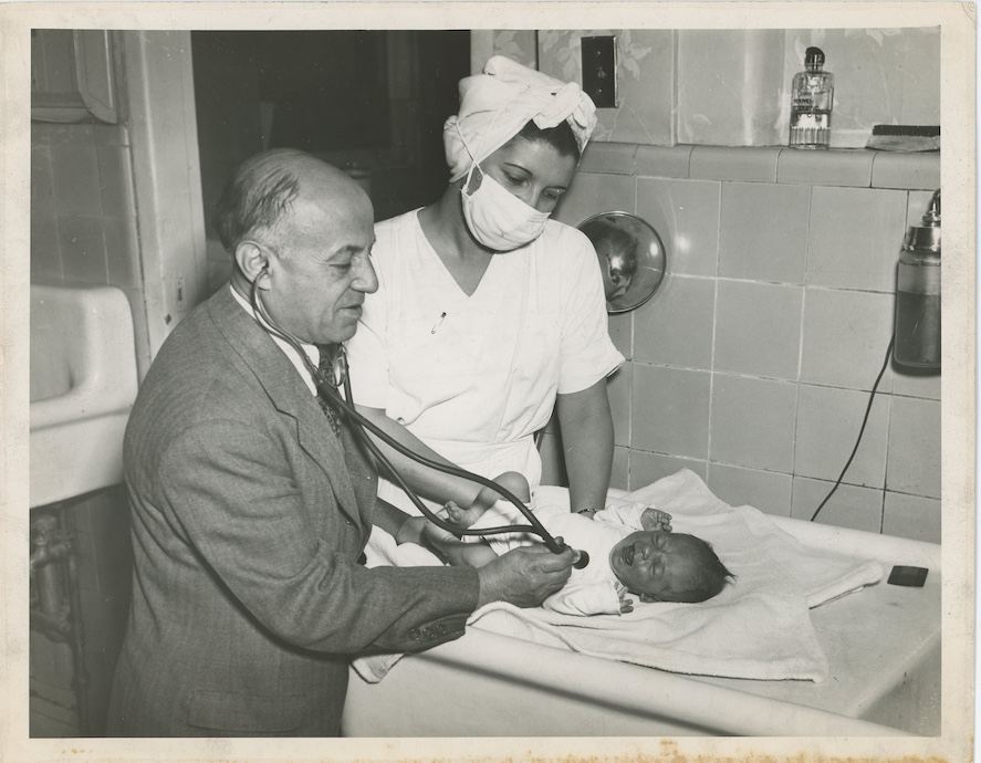 Photo Simpson Studio - Dr. Morris S. Joelson examining a baby with a nurse.