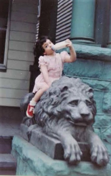 Girl, baby bottle, lion sculpture